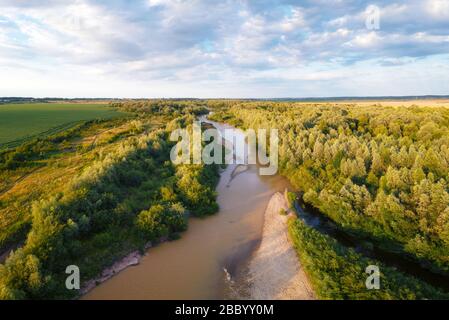 Volo attraverso il maestoso fiume e la lussureggiante foresta verde al tramonto. Fotografia di paesaggio Foto Stock