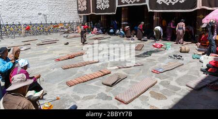 Tappetini di fronte al tempio di Jokhang. Usato per prostrazione da pellegrini buddisti: Far cadere il corpo in avanti e allungarlo per tutta la lunghezza sul pavimento. Foto Stock