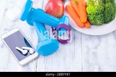 Concetto di fitness con manubri e frutta fresca e verdure. Nutrizione sportiva. Concetto di stile di vita sano con dieta e fitness. Gadget aerobici e uno smartphone per la formazione. Spazio di copia Foto Stock