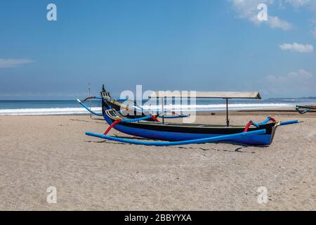 Tradizionale barca da pesca indonesiana in legno (jukung) a Petitenget Beach (Pantai Petitenget). Bali, Indonesia. Foto Stock