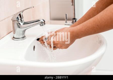 Lavare a mano con sapone in un lavandino in un luogo pubblico. Concetto di igiene. Lavare le mani con sapone sotto il rubinetto con acqua. Foto Stock