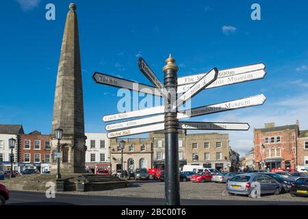 Indicatore di direzione per le attrazioni e il sostanziale obelisco di pietra o croce del mercato nel centro di Richmond nel North Yorkshire Foto Stock