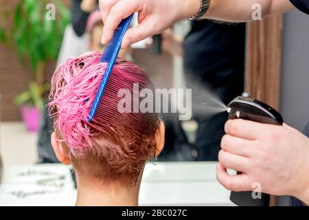 Il parrucchiere spruzza acqua sui capelli della donna primo piano. Foto Stock
