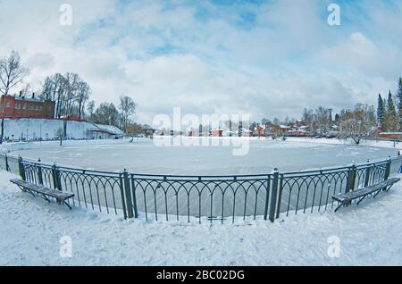 Giorno nevoso invernale in Russia - Stagno Kelarskiy in piccola città Sergiev Posad, cielo blu, acqua ghiacciata, fisheye, distorsione prospettiva, grandangolo. Foto Stock