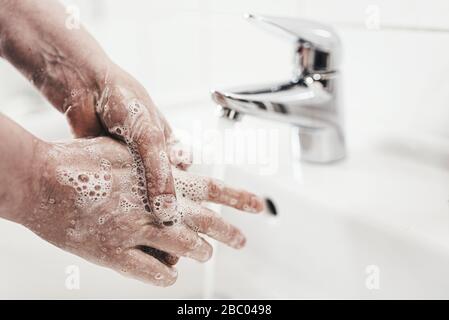 colpo di primo piano di donna che lavava le mani con sapone in lavatorio, misura di igiene durante covid-19 focolaio di coronavirus Foto Stock