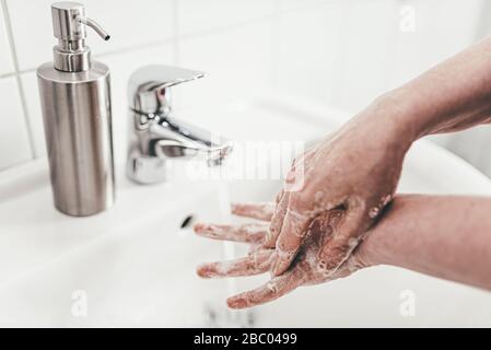 colpo di primo piano di donna che lavava le mani con sapone in lavatorio, misura di igiene durante covid-19 focolaio di coronavirus Foto Stock