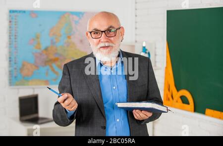 Insegnante di vecchia generazione della scuola. Docente esperto. Insegnante maturo buon insegnamento. Condivisione delle conoscenze. Ottenere certificazioni per programmi specifici. Insegnante di uomo intelligente senior presso la lavagna. Foto Stock