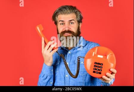 Vieni a trovarci. Tecnologia vintage nella vita moderna. Giovane uomo che parla al telefono. Anziano hippster che mostra il vecchio telefono. Brutale ragazzo con telefono. adulto barbuto uomo parlare su retro telefono. Foto Stock