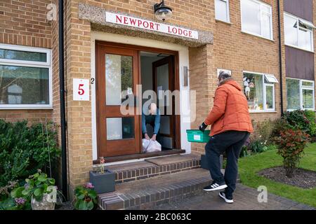 Tony Rosa offre pacchetti alimentari da Enfield Council a Peter Hetherington a Enfield, nel nord di Londra. Foto Stock