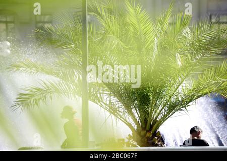 In una calda giornata estiva, i passanti cercano di rinfrescarsi ai margini della fontana di Stachus nel centro di Monaco. [traduzione automatica] Foto Stock