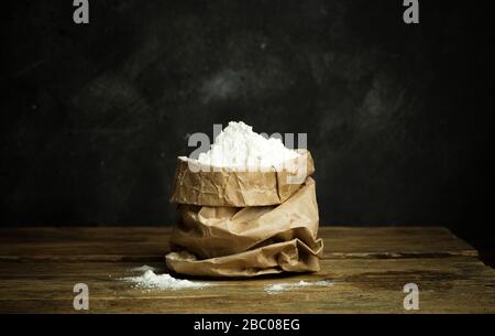 Farina per la cottura di pasta per pizza, pane e pasta su un tavolo di legno e fondo scuro. Concetto di cucina domestica. Foto Stock