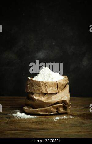 Farina per la cottura di pasta per pizza, pane e pasta su un tavolo di legno e fondo scuro. Concetto di cucina domestica. Foto Stock