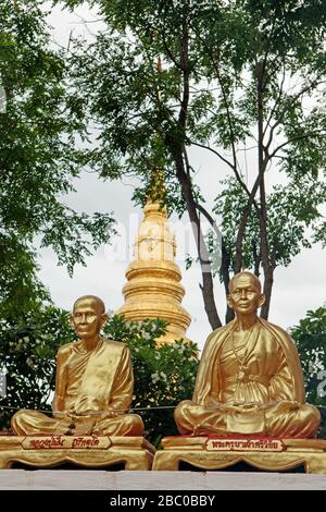 Tra le statue di due monaci dorati seduti si può vedere la famosa pagoda di Wat Phra che Chae Haeng Foto Stock