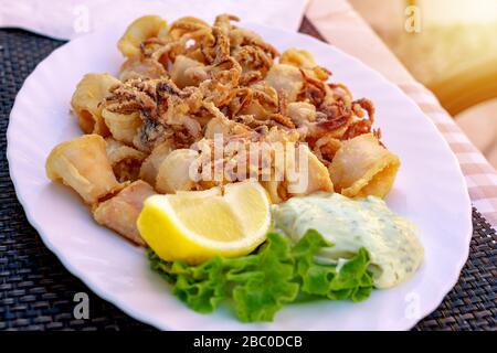 Calamari fritti in un ristorante all'aperto in Croazia con salsa tartare e limone Foto Stock