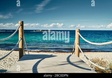 Il percorso verso una spiaggia di mare, un percorso consiste di tavole di legno, su ogni lato una recinzione da una corda di mare, acqua di colore azzurro, tempo libero Foto Stock