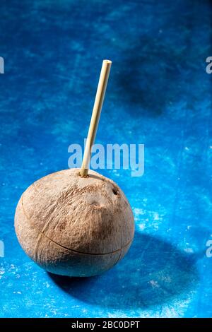 Cocco fresco con cannuccia di bambù inserita su sfondo blu. Zero rifiuti e nessuna plastica. Rifiuto di cannucce da bere in plastica. Cibo sano e ecologico. Foto Stock