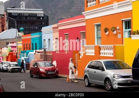 Sud Africa, Città del Capo, Schotsche Knof, Bo Kaap, Wale St, donna guardia parcheggio auto spazio di colorfully dipinto restaurato casa Foto Stock