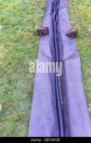 Installazione di una trincea di drenaggio in un prato da giardino, Foto Stock