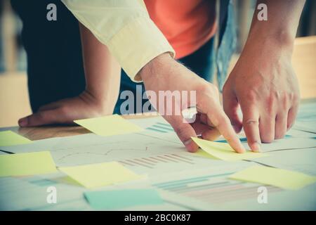 Un gruppo di persone di affari di incontro permanente con i colleghi in sala riunione e visualizzare le prestazioni annuali grafico per analizzare e anticipare il business t Foto Stock