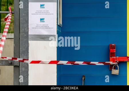 Primo piano di porta capanna di spiaggia con lucchetto con avviso Covid-19 e nastro a strisce rosse e bianche che limitano l'accesso. Foto Stock