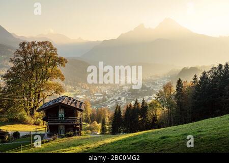 Vista panoramica del tramonto su un idilliaco paesaggio alpino di montagna con un tradizionale Lodge in legno nelle Alpi Bavaresi in una serata d'oro in autunno Foto Stock