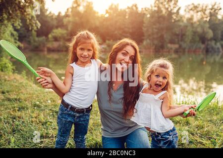 Giorno delle madri. La famiglia si diverte dopo aver giocato a badminton nel parco primaverile. Donna che ride e si addolorava con i bambini Foto Stock
