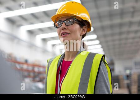 Lavoratore femminile che guarda via in fabbrica Foto Stock