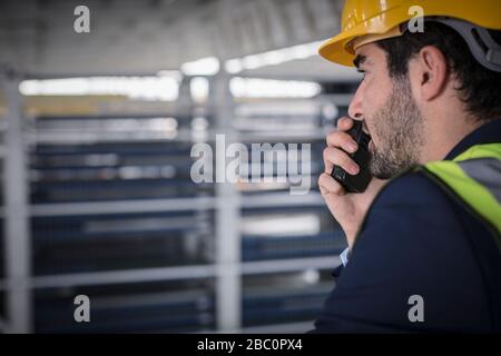 Supervisore maschile che parla, utilizzando walkie-talkie in fabbrica Foto Stock