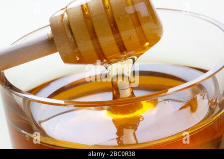 Ciotola di vetro piena di miele legno di miele cucchiaia di miele Foto Stock