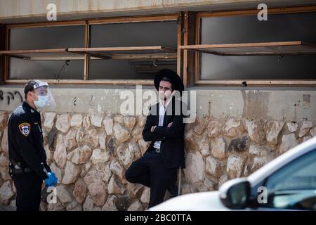 Bnei Brak, Israele. 02nd Apr, 2020. Un poliziotto israeliano parla con un giovane ebreo ortodosso, che insiste a portare avanti con la sua preghiera al Ponevezh Yeshiva, un'istituzione ebraica che si concentra sullo studio dei testi religiosi tradizionali, nonostante il blocco imposto in mezzo alla pandemia del coronavirus. Credit: Ilia Yefimovich/dpa/Alamy Live News Foto Stock