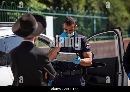 Bnei Brak, Israele. 02nd Apr, 2020. Un poliziotto israeliano conduce un ebreo ortodosso fuori dal Ponevezh Yeshiva, un'istituzione ebraica che si concentra sullo studio dei testi religiosi tradizionali, dove lui e altri insistono a portare avanti la loro preghiera nonostante il blocco imposto in mezzo alla pandemia del coronavirus. Credit: Ilia Yefimovich/dpa/Alamy Live News Foto Stock