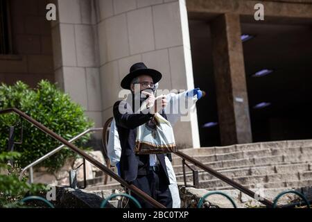 Bnei Brak, Israele. 02nd Apr, 2020. Un poliziotto israeliano in tuta conduce un uomo ebraico ortodosso, fuori dal Ponevezh Yeshiva, un'istituzione ebraica che si concentra sullo studio dei testi religiosi tradizionali, dove lui e altri insistono a portare avanti la loro preghiera nonostante il blocco imposto in mezzo alla pandemia del coronavirus. Credit: Ilia Yefimovich/dpa/Alamy Live News Foto Stock