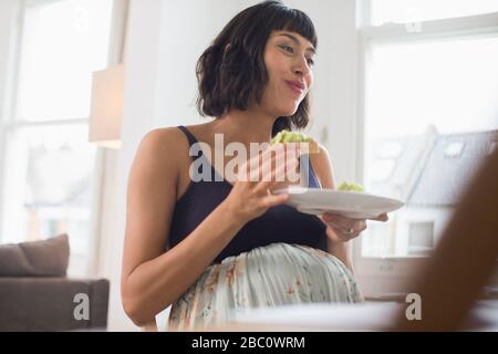 Donna incinta felice che mangia Foto Stock
