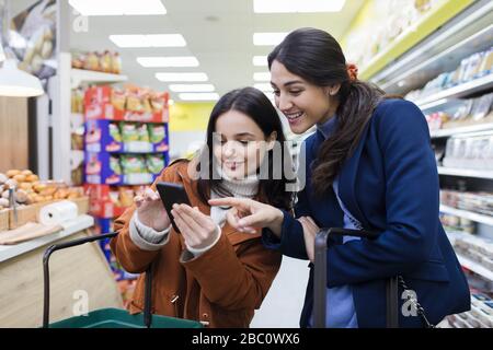 Donne amici con smart phone shopping in supermercato Foto Stock