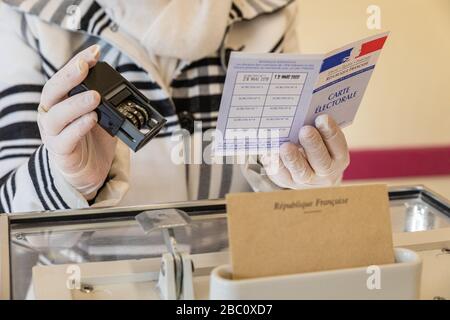 VERIFICA DELLA CARTA DEGLI ELETTORI BFORE IL VOTO, DURANTE IL PRIMO TURNO DELLE ELEZIONI COMUNALI NEL RISPETTO DELLE MISURE SANITARIE ADOTTATE ALLA LUCE DELLA PANDEMIA DI CORONAVIRUS, STAZIONE DI VOTO A RUGLES, NORMANDIA, FRANCIA Foto Stock