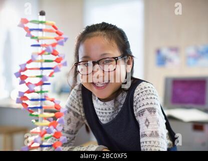 Ritratto sorridente, ragazza sicura studente accanto al DNA modello in classe Foto Stock