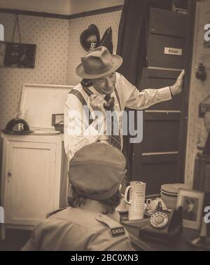 Vintage seppia vista frontale 1940 s uomo che indossa trilby al telefono nella sala degli anni '40, Severn Valley Railway 1940's fine settimana estate evento, Regno Unito. Ferrovie del patrimonio. Foto Stock