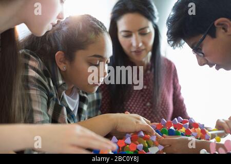 Studenti curiosi che esaminano il modello del DNA in classe Foto Stock