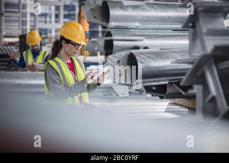 Supervisore femminile che utilizza un tablet digitale in una fabbrica di acciaio Foto Stock