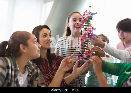 Insegnante femminile e studenti che esaminano il modello del DNA in classe Foto Stock