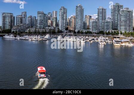 Coal Harbour con piccolo traghetto adornato con la bandiera di Maple Leaf, Vancouver, BC, Canada Foto Stock