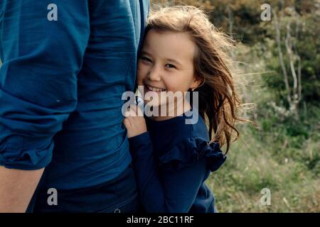 Ritratto di ragazza ridente che si nasconde dietro la schiena del padre Foto Stock