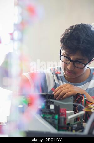 Studente ragazzo concentrato che monta il computer in classe Foto Stock