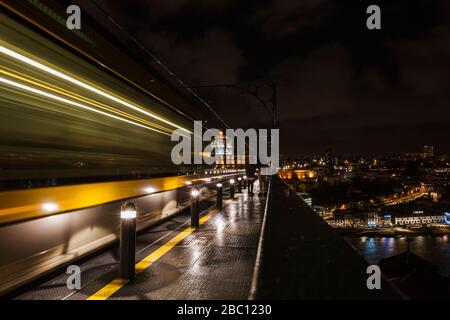 Portogallo, Porto, movimento sfocato del treno della metropolitana che passa la ferrovia sopraelevata di notte Foto Stock