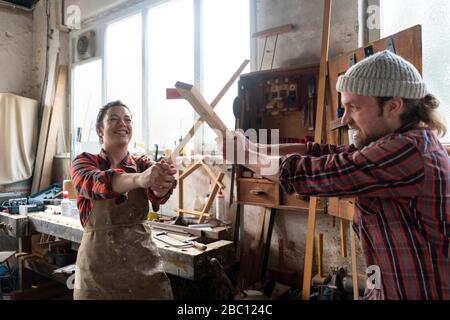 Giocosa pastinzia e artigiano lotta nella loro officina Foto Stock