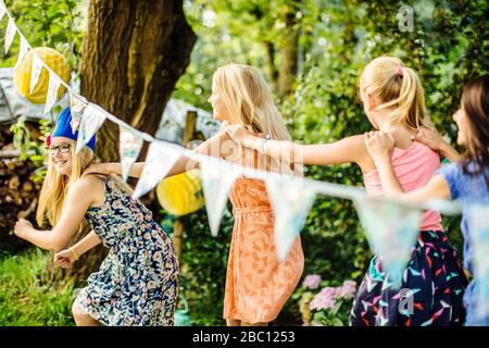 Ragazze felici che fanno una linea di conga su una festa di compleanno all'aperto Foto Stock