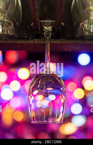 Wineglass vuoto appeso sul banco con luci bokeh in background Foto Stock