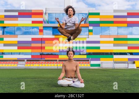 Donna meditating sul prato, uomo che si sorpassa sopra lei, meditating, anche Foto Stock