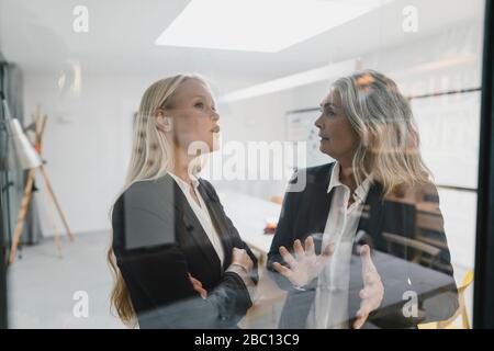 Donna d'affari matura e giovane che parla in loft ufficio Foto Stock