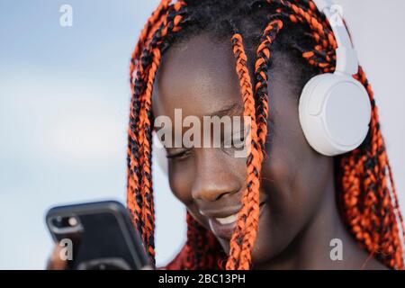 Ritratto di ragazza sorridente con cuffie e smartphone all'aperto Foto Stock